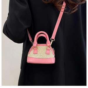 Rosa Mini-Muscheltasche aus Stroh-Patchwork am Modell mit goldenen Metallelementen