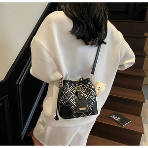 Detail of geometric pattern bucket bag featuring gold hardware and plush charm pendant