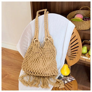Détail d'un sac à bandoulière tressé avec franges et anneaux en bois pour la poignée