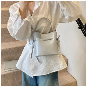 Close-up of light blue bucket bag with metallic strap and drawstring texture details