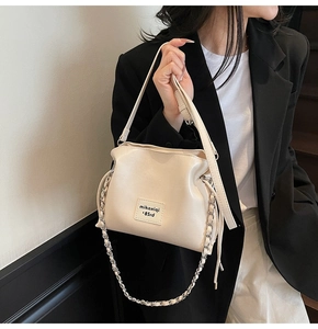 Detail of cream leather bucket bag showing silver chain strap and brand logo patch