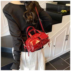 Vue latérale d'un sac bowling en cuir verni rouge brillant avec poches à lacets décoratives