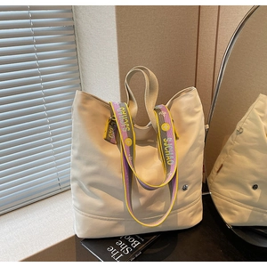 Detail of canvas tote bag showing two-tone wide strap and side metal buckle details