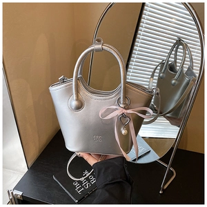 Détail du sac seau argenté avec ruban rose, breloque coeur et accents de perles