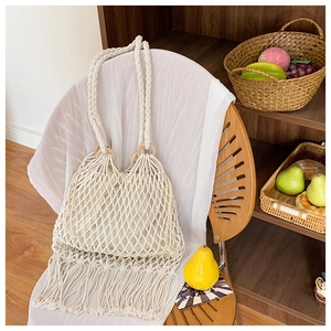 Détail du sac en maille tissé main avec de longues franges et une poignée ronde en bois
