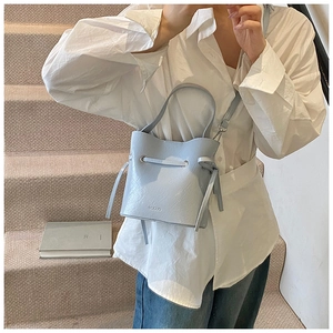 Close-up of light blue drawstring bucket bag with textured faux leather and MUDUO logo