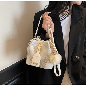 Detail of jacquard bucket bag with white leather trim and plush sheep pendant charm