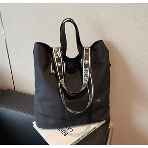 Detail of black nylon tote bag with decorative jacquard shoulder strap on a magazine