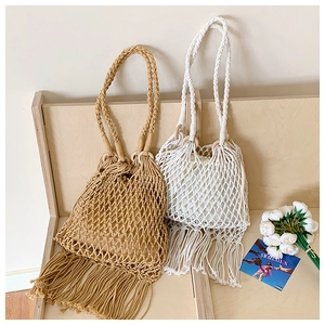 Détail de sacs en paille tressée avec poignées rondes en bois et longues franges