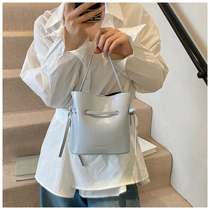Close-up of light blue pleated bucket bag with metal eyelets and drawstring detail