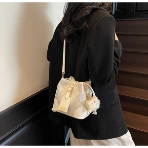 Detailed side view of off-white drawstring bucket bag with beige geometric patterns