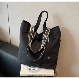 Detail of black nylon tote bag with patterned wide strap on Business Layout book