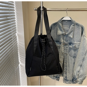 Detail of black nylon drawstring tote bag with woven straps and side brand label