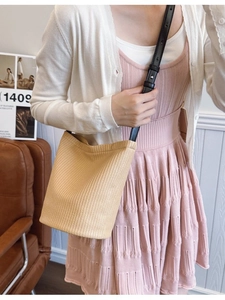 Minimalist woven bucket bag with black leather strap in casual lifestyle setting