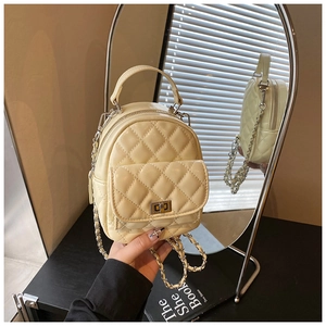 Dettaglio di un mini zaino trapuntato beige con chiusura girevole e tracolla a catena