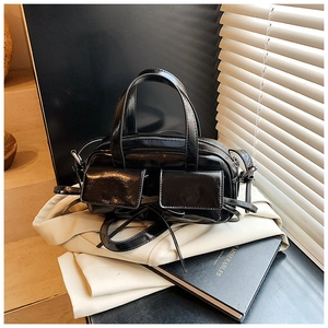 Détail d'un sac bowling en cuir noir brillant avec poches décoratives et deux poignées