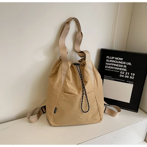 Detail of khaki drawstring tote bag featuring side pocket and durable nylon fabric