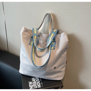 Detail of lavender canvas tote bag with jacquard shoulder strap and metal logo emblem