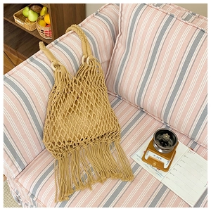Détail d'un sac en filet tissé main avec anses en bois et longues franges style bohème