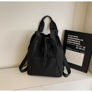Detail shot of black nylon drawstring backpack featuring white textured cords and side logo