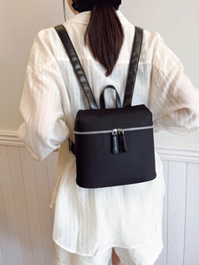 Minimalist black nylon backpack for women with leather handles and silver zippers