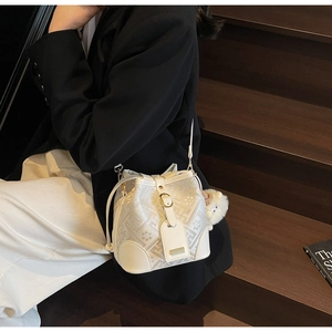 Detail of white bucket bag with gray floral patterns and cute plush lamb pendant