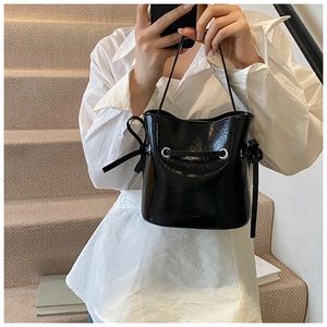 Mirror selfie showing a black glossy bucket bag with silver eyelets and drawstring strap