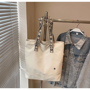 Detail of cream tote bag with woven SJCHAO letter print shoulder strap and leather texture