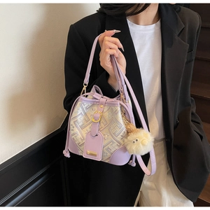 Detail view of purple bucket bag featuring geometric fabric texture and plush sheep charm