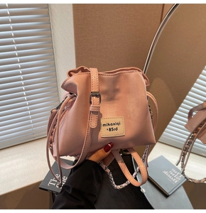 Close-up of pink drawstring bucket bag with leather strap and metal chain detail