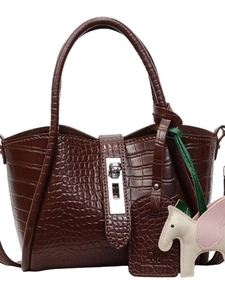 Dark brown crocodile embossed handbag with silver lock and pony charm on white background