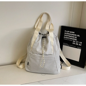 Detailed view of checkered drawstring bucket backpack with woven handles and cord lock