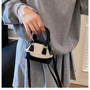 Details der Mini-Muscheltasche mit beiger Webstruktur und schwarzem Lederfinish