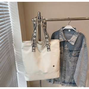 Detail of white tote bag featuring woven sjchao floral handles and reinforced stitching