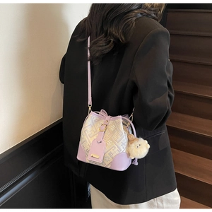 Detail view of purple leather bucket bag with jacquard fabric and plush monster charm