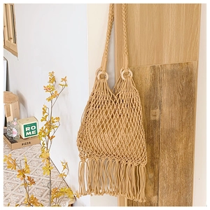 Détail du sac bohème tissé avec de longues franges et une poignée en bois ronde