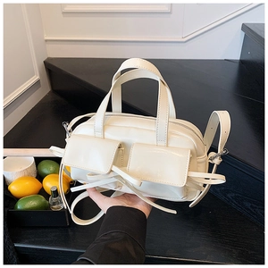Détail du sac Boston crème en cuir brillant avec poches ornées de franges élégantes