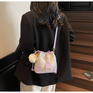 Detail of lavender bucket bag with geometric pattern and plush charm on a model