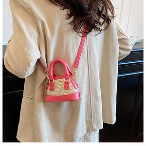 Mini-Muschel-Umhängetasche mit rosa Lederbesatz und Strohgeflecht-Detail am Modell