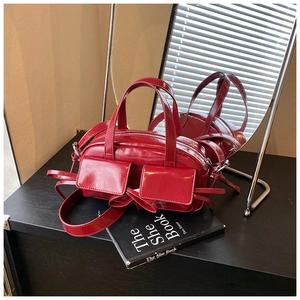 Détail de sac rouge brillant avec doubles poches avant et décorations de nœuds élégants