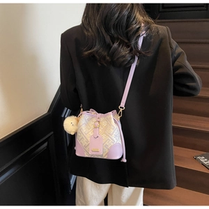 Detail of purple color-block bucket bag with floral jacquard fabric and plush pompom charm