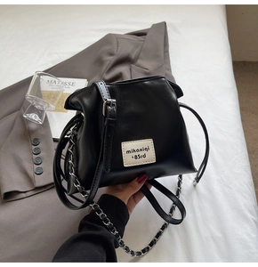 Detail of black PU leather bucket bag with silver chain handle and white brand label