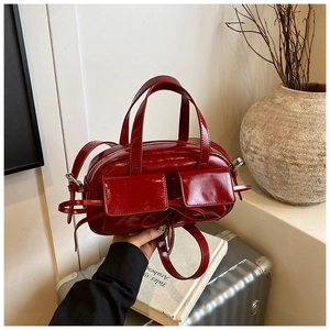 Détail du sac bowling en cuir verni rouge avec poches avant et décoration de nœud