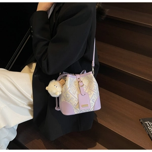 Detail of lavender patchwork bucket bag with geometric jacquard and furry monster charm