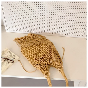 Détail d'un sac en maille beige tissé main avec poignées rondes en bois et glands bohèmes