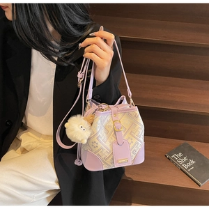 Detail of lavender geometric jacquard bucket bag with plush charm and leather straps