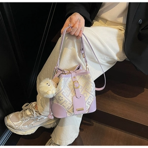 Detail of lavender bucket bag with geometric patterns and plush pendant shown on stairs