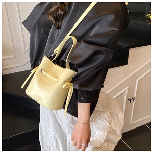 Detail view of cream bucket bag with drawstring closure and engraved brand logo