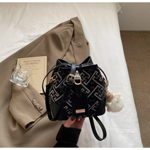 Detail of black jacquard bucket bag with geometric patterns and plush pendant charm
