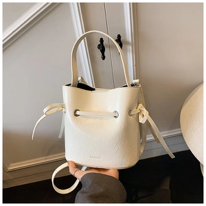 Detail of cream white bucket bag showing drawstring bows and embossed logo on leather